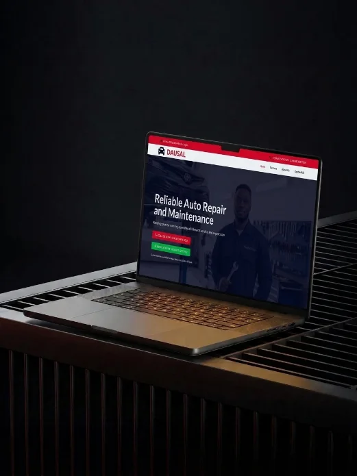Laptop on a dark table showing the Dausal auto repair website homepage